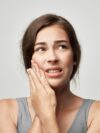 Frau mit Kiefergelenkschmerzen – typisches Symptom bei CMD